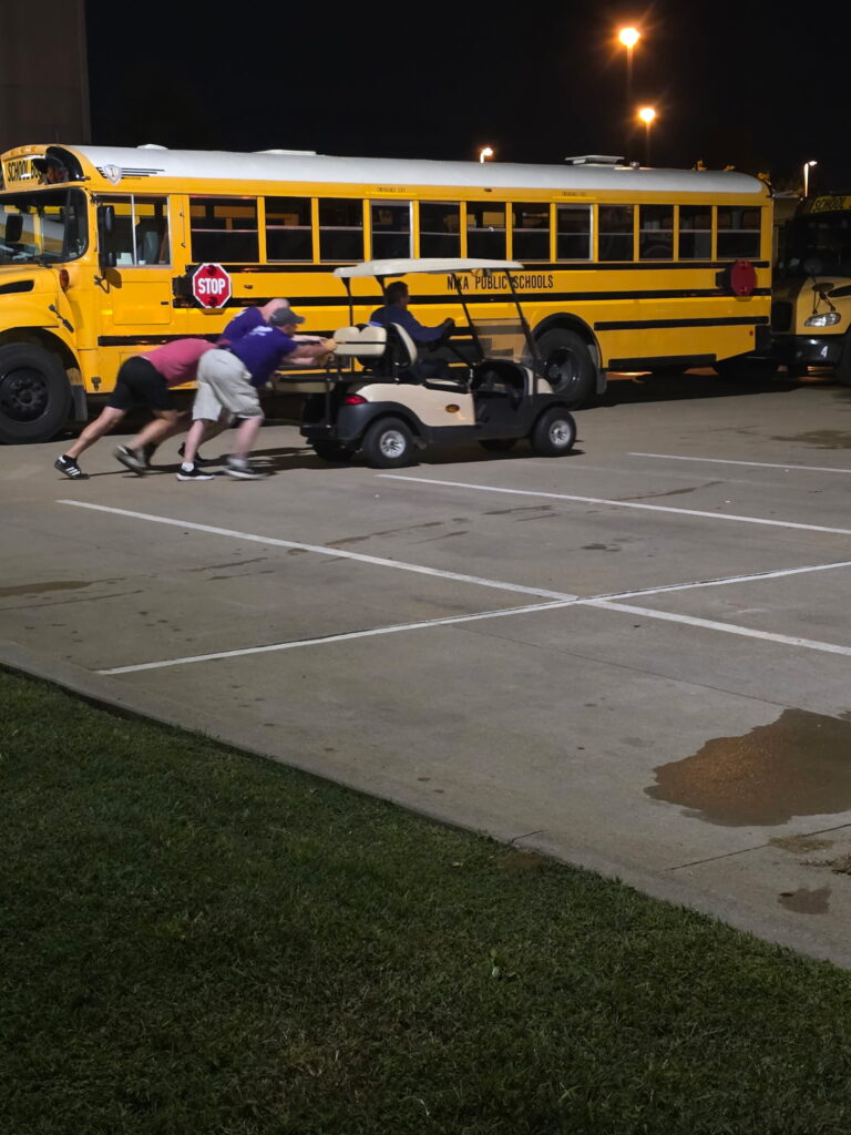 Bus parent volunteers helping move equipment after dark