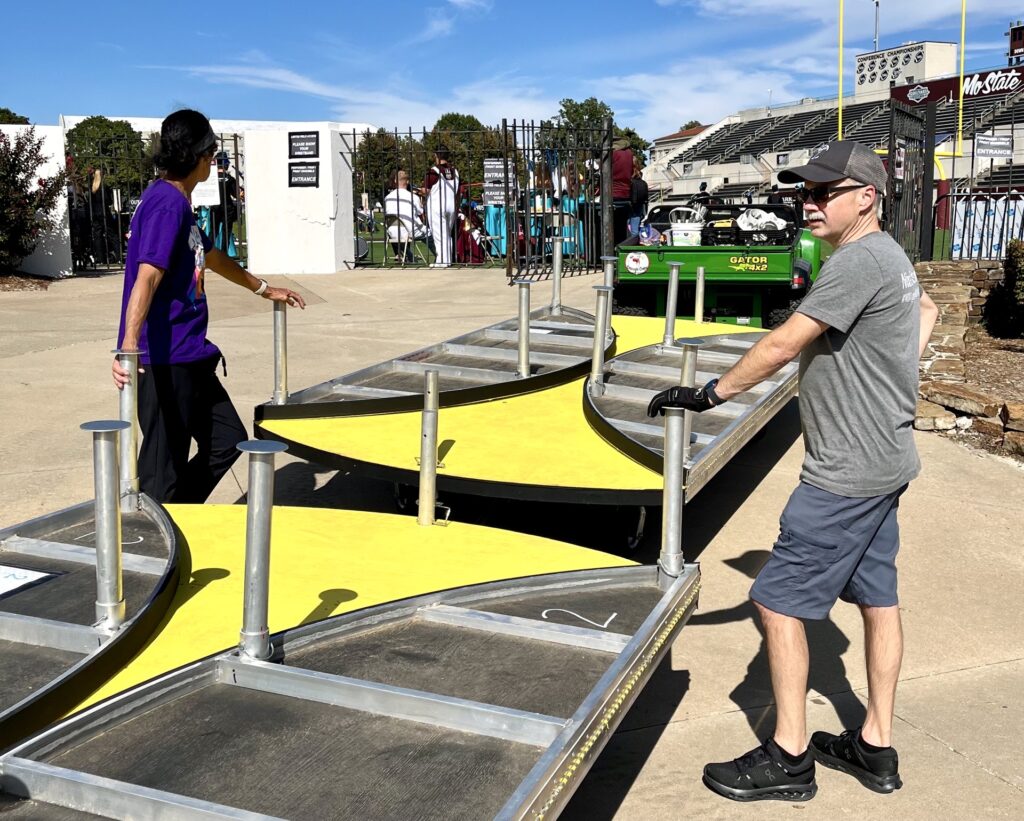 Prop crew volunteers moving staging pieces into place