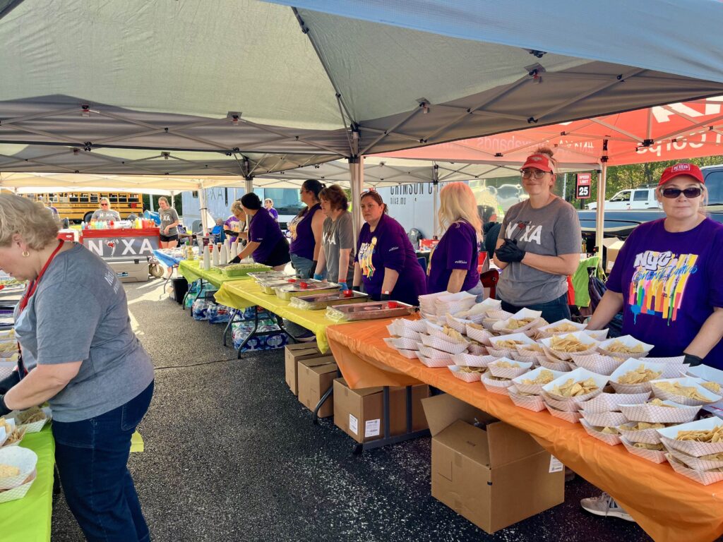 Hospitality volunteers serving snacks under the tent